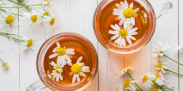 Xícara de chá e camomila flores sobre fundo de madeira | Foto Premium